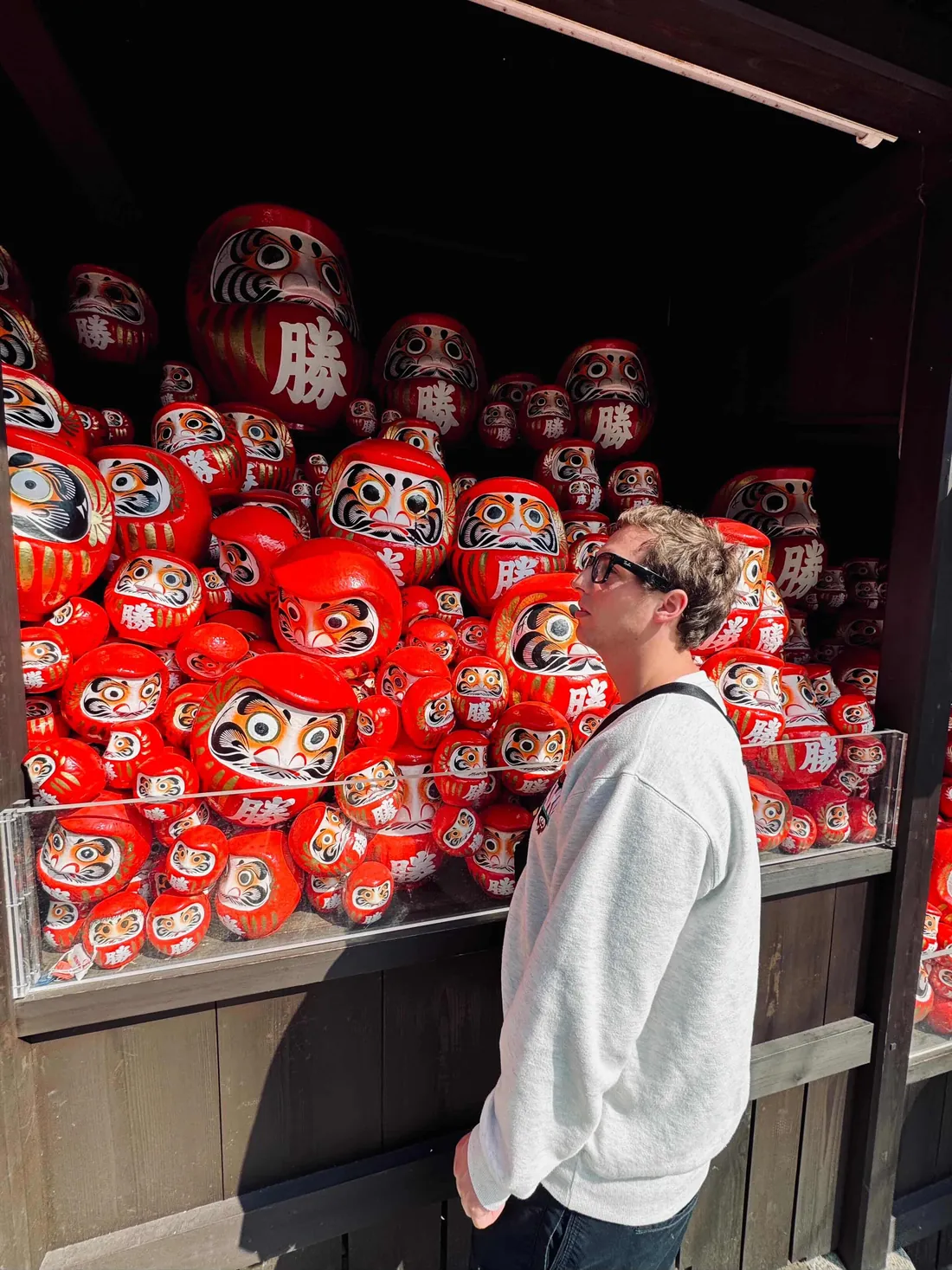 Jérémy devant le mur de daruma d’un temple d’Osaka